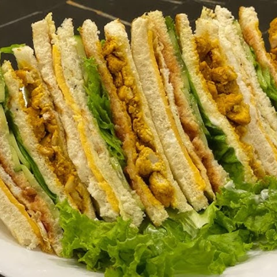 Club sandwiches with chicken, cheese, and lettuce, arranged on a white plate with green lettuce.